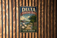 A vintage metal sign for Delta Heritage Trail in Arkansas, featuring a scenic illustration of a river, cotton fields, and a steamboat.