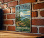 A vintage metal sign for Denton Hill State Park in Pennsylvania, featuring a scenic landscape with a river and forest.