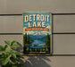 A vintage metal sign for Detroit Lake, Oregon, featuring a scenic mountain landscape with a boat on the lake.