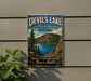 A vintage-style sign for Devil's Lake, Oregon, featuring a scenic mountain landscape with pine trees and a lake.
