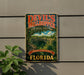 A vintage-style sign for Devil's Mill Hopper, a geological state park in Florida, featuring a scenic image of the park's landscape.
