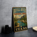 A vintage-style metal sign for the Devils River State Natural Area in Texas, featuring a scenic landscape with a river, mountains, and desert vegetation.