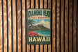 A vintage-style metal sign for the Diamond Head State Monument in Hawaii, featuring a tropical landscape with a mountain, palm trees, and a beach.