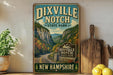 a vintage-style sign for Dixville Notch State Park in New Hampshire, with a scenic mountain landscape and a road winding through the valley.