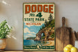 A vintage Dodge sign advertising No. 4 State Park in Michigan, featuring a scenic landscape with a lake, cliffs, and pine trees.