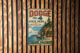 A vintage metal sign for Dodge State Park in Michigan, featuring a scenic illustration of a cliff overlooking a lake.