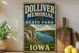 A vintage-style sign for Dolliver Memorial State Park in Iowa, featuring a scenic landscape with a river and mountains.