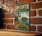 A vintage-style metal sign for Don Carter State Park in Georgia, featuring a scenic landscape with a lake and trees.