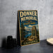 A vintage-style sign for Donner Memorial State Park in California, featuring a scenic landscape with mountains, pine trees, and a lake.