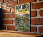 A vintage-style metal sign for Dos Rios State Park in California, featuring a scenic illustration of a river and mountains.