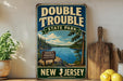 A vintage-style sign for Double Trouble State Park in New Jersey, featuring a scenic landscape with a lake and pine trees.