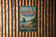 A vintage metal sign for Doug's Beach State Park in Washington, featuring a scenic landscape with a mountain, beach, and pine trees.
