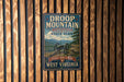 A vintage metal sign for Droop Mountain Battlefield State Park in West Virginia, featuring a cannon and a scenic mountain landscape.