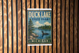 A vintage-style sign for Duck Lake State Park in Michigan, featuring a lake scene with a loon and trees, mounted on a wooden wall.
