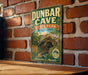 A vintage-style sign for Dunbar Cave State Park in Tennessee, featuring a cave illustration and the text "Adventures Await".