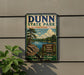 A vintage metal sign for Dunn State Park in Massachusetts, featuring a scenic landscape with a lake, pine trees, and mountains.