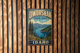 A vintage metal sign for Dworshak State Park in Idaho, featuring a scenic landscape with mountains, pine trees, and a lake.