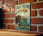 A vintage-style metal sign for Eagle Island State Park in Idaho, featuring an eagle perched on a tree branch with a lake and mountains in the background.