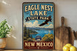 A vintage-style sign for Eagle Nest Lake State Park in New Mexico, featuring a scenic landscape with a bald eagle in flight.