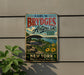 A vintage-style metal sign for "Earl W. Brydges Artpark State Park New York" is displayed on a wall, featuring a scenic image of a bridge and a river.