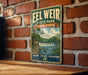 A vintage-style metal sign for Eel Weir State Park in New York, featuring a scenic landscape with a waterfall and trees.