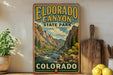 A vintage-style poster of Eldorado Canyon, a state park in Colorado, is displayed on a wall next to a wooden cutting board and some kitchen utensils.