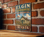 A vintage-style metal sign for Elgin Schoolhouse, a historic site in Nevada, is displayed on a brick wall.