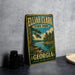 A vintage-style metal sign for Eljah Clark State Park in Georgia, featuring a scenic landscape with a lake and trees.
