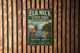 A vintage metal sign for Elk Neck State Park, Maryland, featuring an illustration of a deer in a wooded area with a body of water in the background.