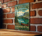 A vintage-style metal sign for Emerald Lake State Park in Vermont, featuring a scenic landscape with a lake, mountains, and a canoe.
