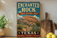 A vintage-style sign for the Enchanted Rock State Natural Area in Texas, featuring a scenic illustration of the rock formation and desert landscape.