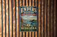 A vintage metal sign for the Enders Reservoir State Recreation Area in Nebraska, featuring a scenic landscape with a lake, mountains, and a boat.