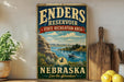 A vintage-style sign for the Enders Reservoir State Recreation Area in Nebraska, featuring a scenic landscape with a lake, mountains, and a boat.
