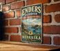 A vintage metal sign for the Enders Reservoir in Nebraska, featuring a scenic landscape with a lake, mountains, and a boat.