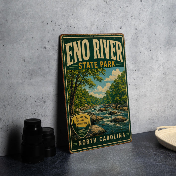 A vintage-style metal sign for Eno River State Park in North Carolina, featuring a scenic illustration of a river and forest landscape.