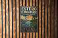 A vintage-style metal sign for Estero Llano Grande State Park in Texas, featuring a large blue heron and a scenic landscape.