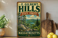 A vintage-style metal sign for F. Gilbert Hills State Forest in Massachusetts, featuring a scenic landscape with pine trees, a lake, and mountains.