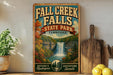 A vintage-style sign for Fall Creek Falls State Park in Tennessee, featuring a scenic image of the waterfall surrounded by autumn foliage.