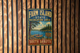 A vintage-style metal sign for Farm Island State Recreation Area in South Dakota, featuring a scenic landscape with a lake, pine trees, and a boat.