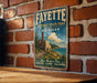 A vintage metal sign for Fayette Historic State Park in Michigan, featuring a scenic illustration of a lighthouse and a coastal landscape.