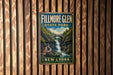 A vintage metal sign for Fillmore Glen State Park in New York, featuring a scenic image of a waterfall surrounded by lush greenery.
