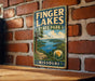 A vintage-style metal sign for Finger Lakes State Park in Missouri, featuring a scenic landscape with a lake and mountains.