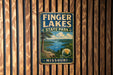 A vintage metal sign for Finger Lakes State Park in Missouri, featuring a scenic landscape with a lake and mountains.