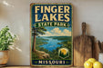 A vintage-style sign for Finger Lakes State Park in Missouri, featuring a scenic landscape with a lake, mountains, and a boat on the water.