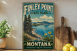 A vintage-style sign for Finley Point State Park in Montana, featuring a scenic landscape with pine trees, a lake, and mountains.