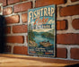 A vintage-style sign for Fish Trap Lake State Park in Kentucky, featuring a scenic illustration of a lake with a boat and mountains in the background.