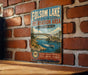A vintage metal sign for Folsom Lake State Recreation Area in California, featuring a scenic illustration of a bridge over a river with boats and people enjoying the outdoors.