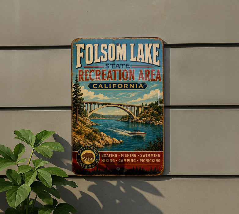 A vintage metal sign for Folsom Lake State Recreation Area in California, featuring a scenic illustration of a bridge over a river with boats and people enjoying the outdoors.