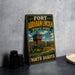 A vintage-style metal sign for Fort Abraham Lincoln State Park in North Dakota, featuring an illustration of a cannon and a wooden building.
