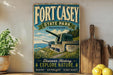 A vintage-style sign for Fort Casey State Park in Washington, featuring a scenic image of the park's cannons and surrounding landscape.